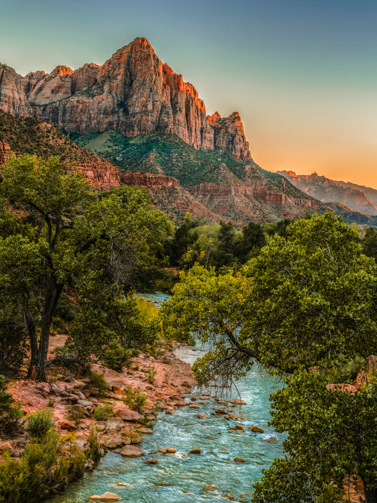 Sunset Glow on Towering Sandstone Cliffs Over Verdant River Valley