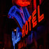 Neon sign for a hotel with blue and red colors against a dark background