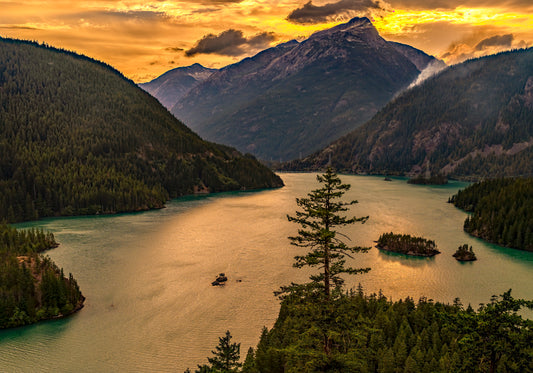 Mountainous landscape with a lake and trees at sunset