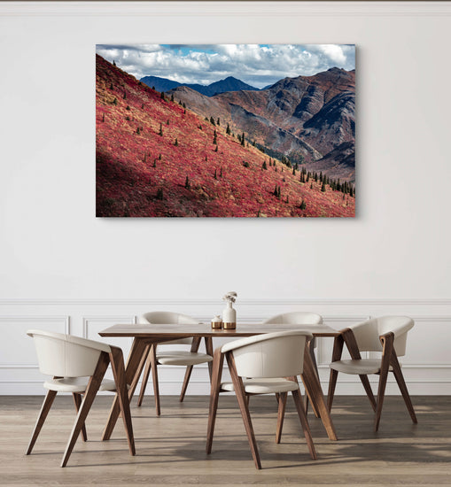 Dining room with a large landscape painting of mountains and trees on the wall.