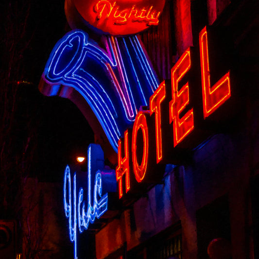 Neon sign for a hotel with blue and red colors against a dark background